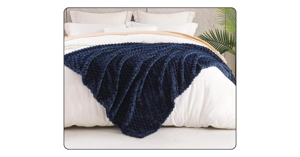 Cozy navy throw blanket styled on a luxury bedroom bed.